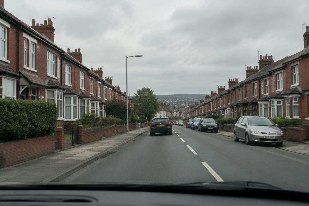 View from a car driving down a British terraced street on a morning commute